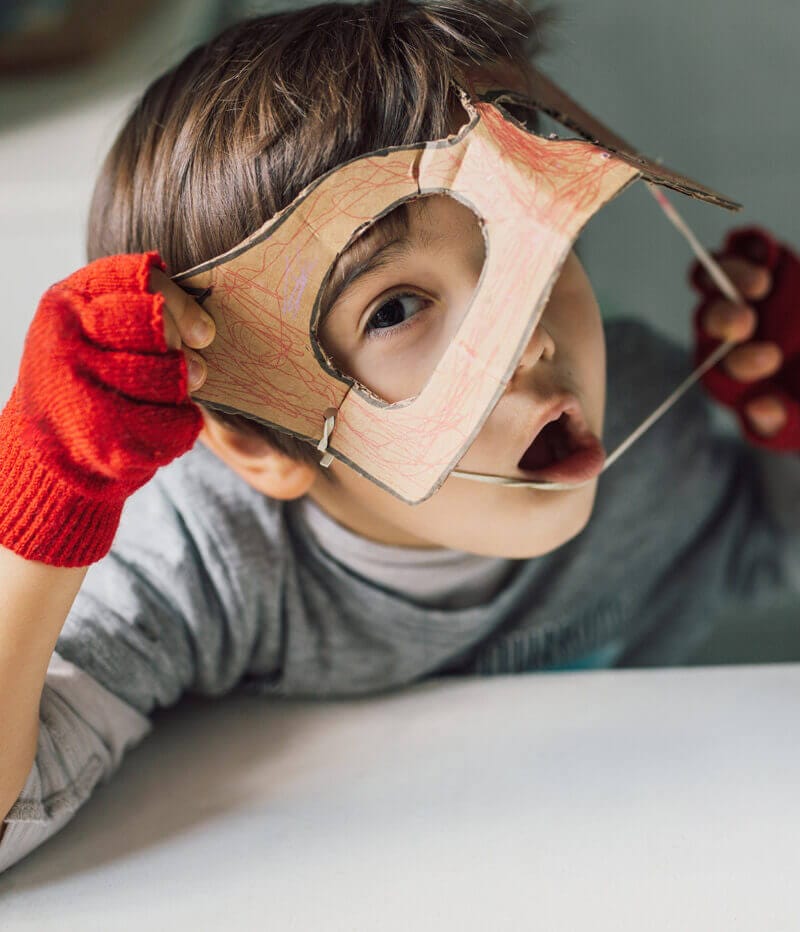 liten kille sätter på en ansiktsmask i papper
