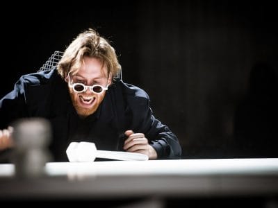 Galen man vid ett runt bord i verket Vanmakt.