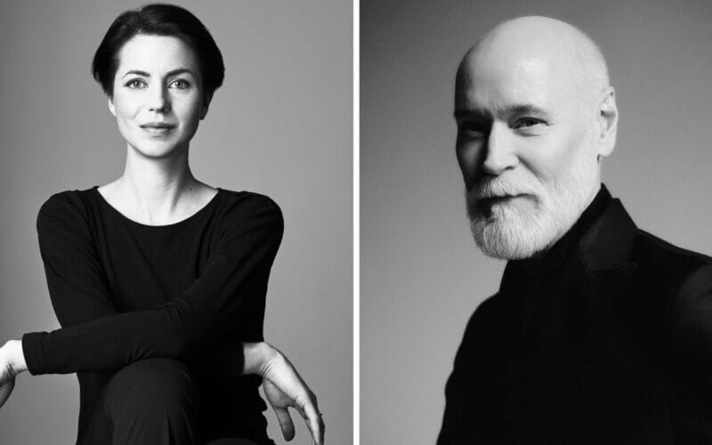 Svartvita porträtt av en kvinna med kort mörkt hår och en man med vitt skägg, båda i mörka kläder, fångar den tidlösa elegansen som firas i Lars Wallin Atelier – 35 Years of Fashion Stories.
