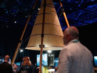 Deltagarna samlas runt en stor, upplyst, konisk tältliknande struktur inne i det svagt upplysta evenemangsutrymmet och surrar av spänning inför Arrow Innovation Awards 2024.