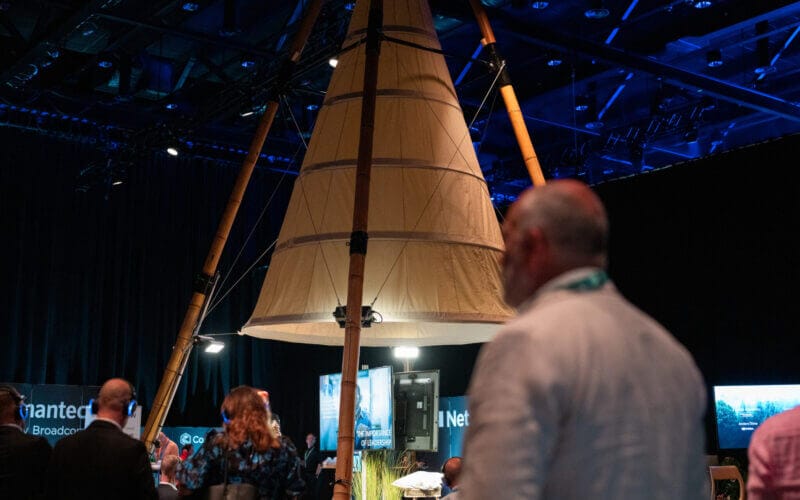 Deltagarna samlas runt en stor, upplyst, konisk tältliknande struktur inne i det svagt upplysta evenemangsutrymmet och surrar av spänning inför Arrow Innovation Awards 2024.