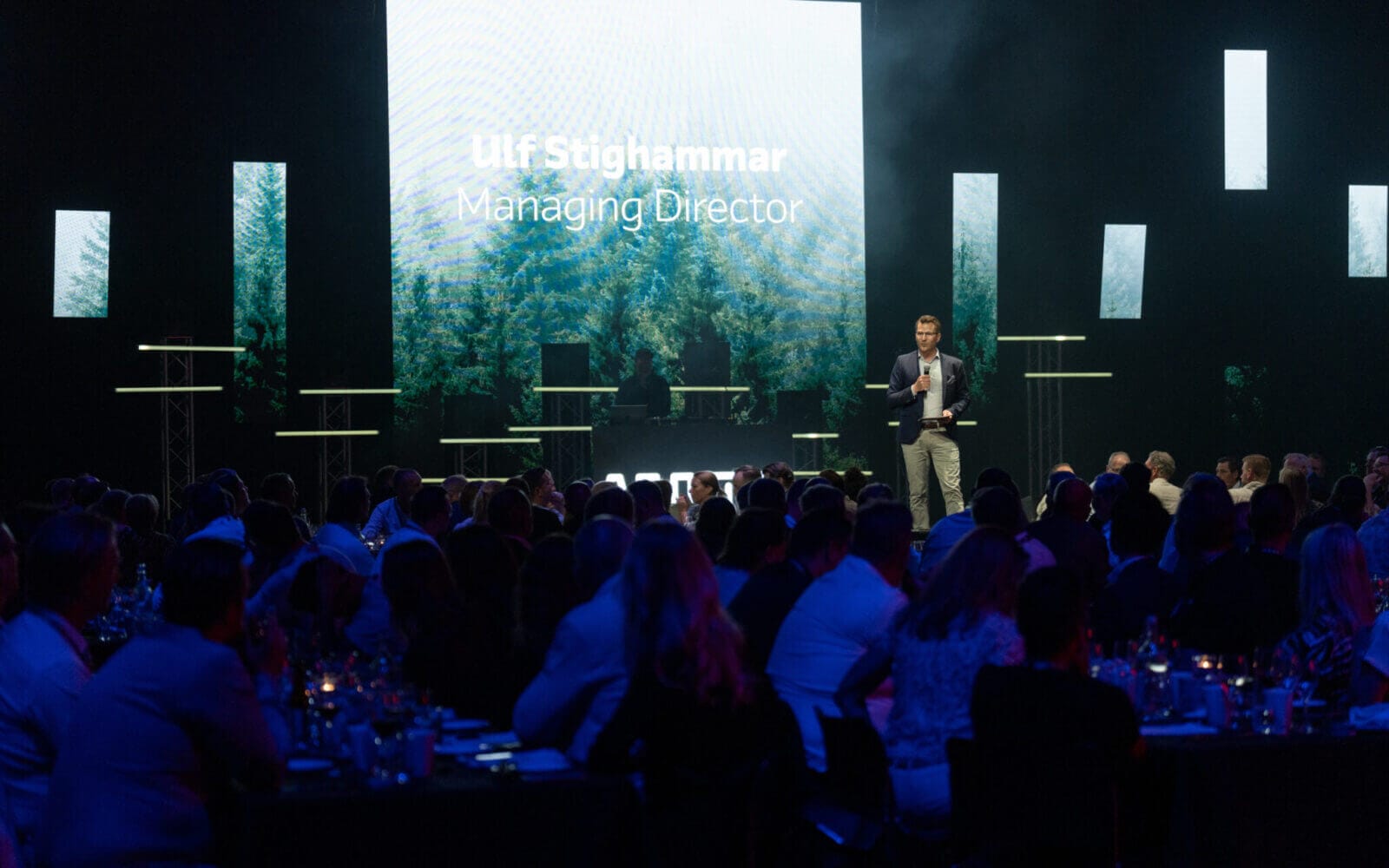 En man talar på scenen inför publik, med en stor skärm som visar "Ulf Stighammar, VD." Bakgrunden har en fridfull skog och den prestigefyllda Arrow Innovation Awards 2024-logotypen.