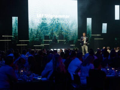 En man talar på scenen inför publik, med en stor skärm som visar "Ulf Stighammar, VD." Bakgrunden har en fridfull skog och den prestigefyllda Arrow Innovation Awards 2024-logotypen.