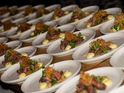 Rader av gourmetbifftallrikar, prydda med stekt lök, grönt och krämig sås, väntar i förväntan på en träyta. Kan denna utsökta presentation vara en utmanare till Arrow Innovation Awards 2024?.