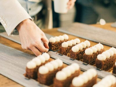 Person som ordnar rader av skivade kakor toppade med vit glasyr på träbrickor.