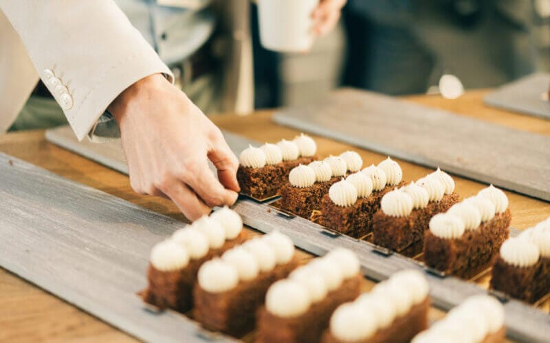 Person som ordnar rader av skivade kakor toppade med vit glasyr på träbrickor.