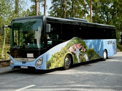 En buss med en ljusblå foliering och en bild över Artipelags byggnad och naturmarker.