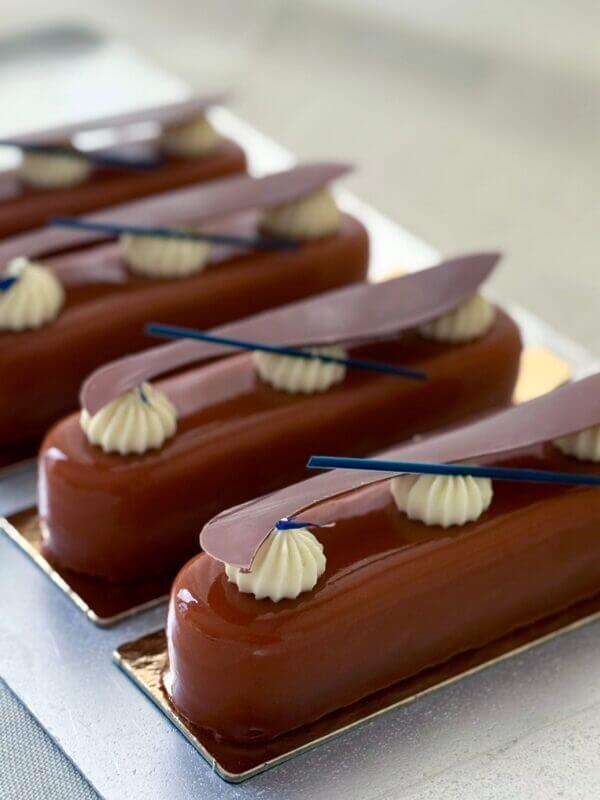 Bilden föreställer brunorangea bakelser uppradade på ett rostfritt fat. Bakgrunden är ett vitt linnetyg.