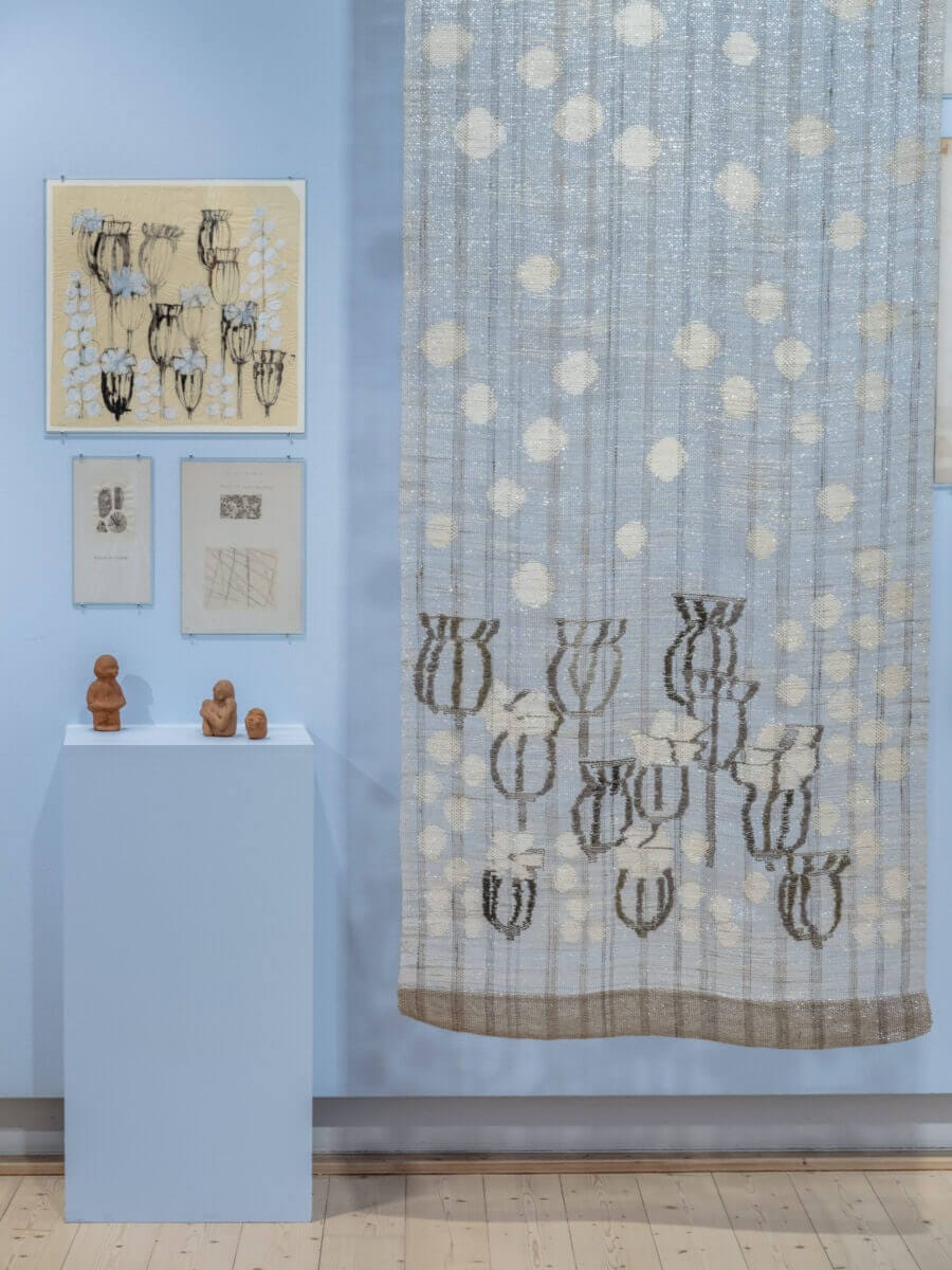 Utställningsbild från utställningen Mitt kreativa liv. Bilden föreställer olika arbeten från Konstfack som hänger på, och är placerade mot, en ljusblå vägg - textilier, skisser och skulpturer.