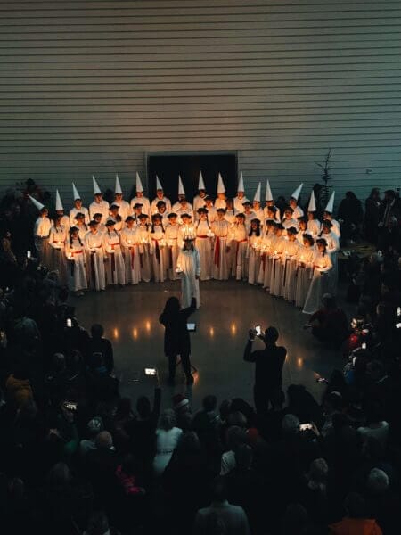 Luciatåg som står uppradade och sjunger framför publik i foajén på Artipelag.