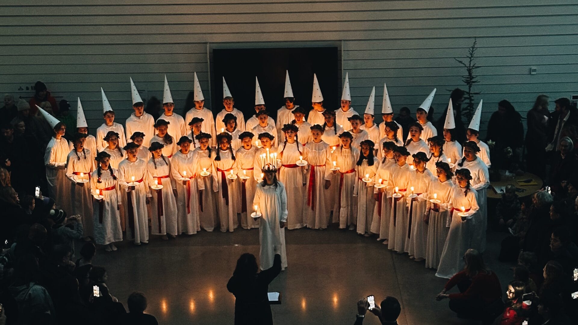 Luciatåg som står uppradade och sjunger framför publik i foajén på Artipelag.
