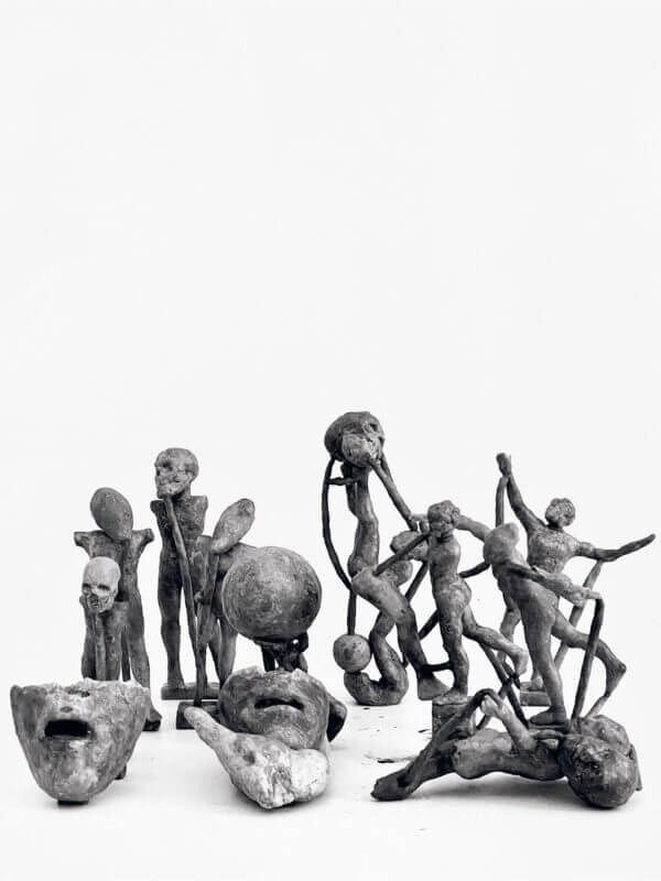A collection of abstract, rough-textured clay sculptures by Fredrik Wretman, depicting human figures and faces arranged against a plain white background.