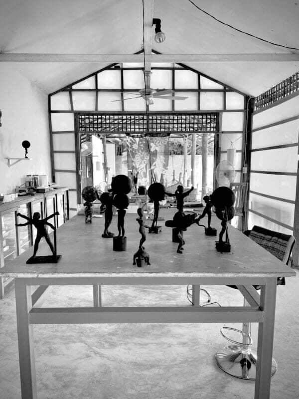 En svartvit bild på ett bord med skulpturer på. I bakgrund syns dekorativa fönster och en entréöppning.