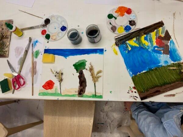 Ett barn som sitter vid ett bord med teckningar.